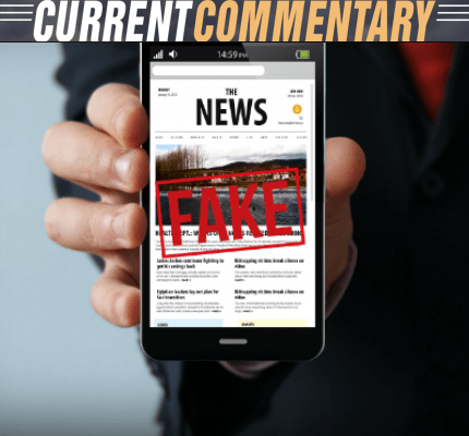 Person holding a cell phone that says fake on a news site